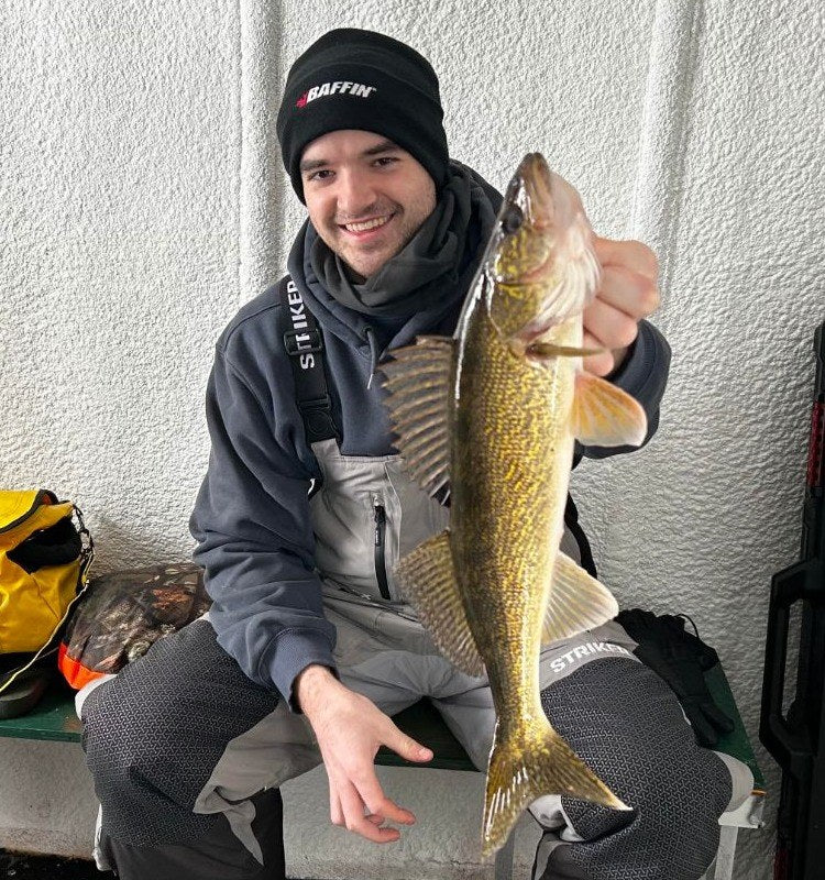 Sean G. smiling on the ice, holding a walleye
